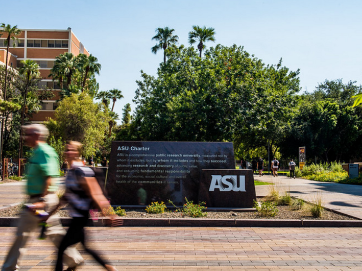 ASU sign at Tempe campus and two people walking by