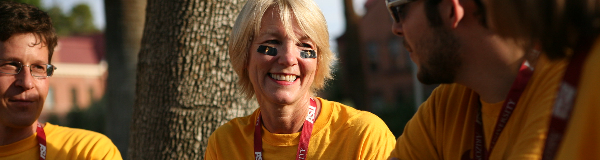 three people sitting down smiling and wearing ASU gold shirts