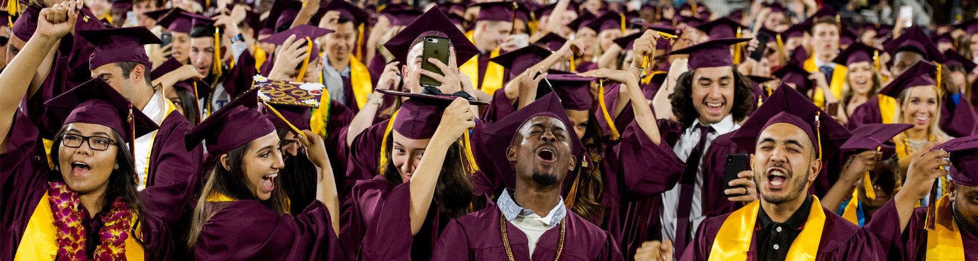 Cheering students in their caps and gowns during graduation.
